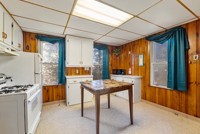 kitchen featuring white cabinetry, white gas range oven, and wood walls