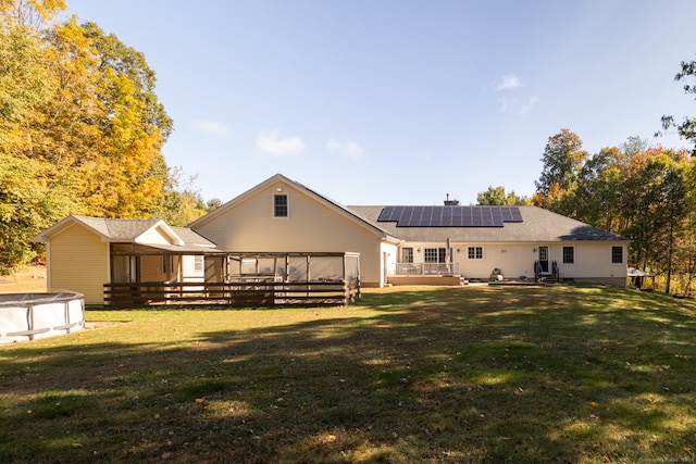 rear view of house featuring a yard, a pool side deck, and solar panels