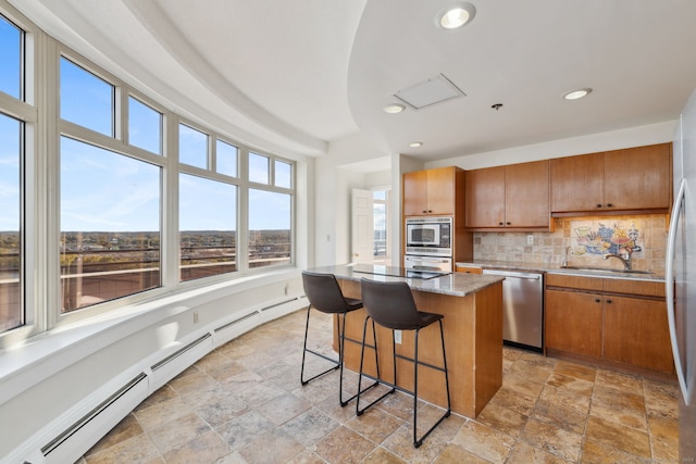 kitchen featuring appliances with stainless steel finishes, sink, a center island, baseboard heating, and decorative backsplash