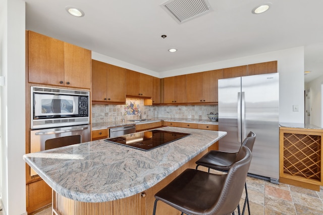 kitchen with backsplash, appliances with stainless steel finishes, a kitchen bar, and a kitchen island