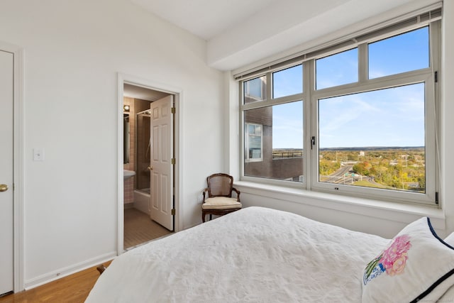 bedroom featuring hardwood / wood-style floors, multiple windows, and ensuite bath