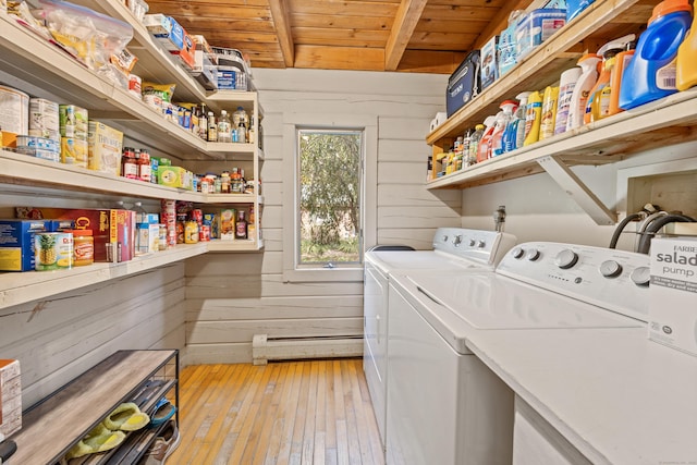 washroom featuring washing machine and clothes dryer, wooden ceiling, light hardwood / wood-style flooring, a baseboard heating unit, and wood walls