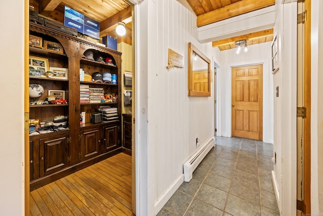 hallway with baseboard heating, wooden ceiling, beamed ceiling, tile patterned flooring, and wood walls