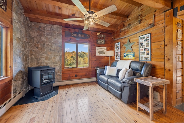 living room with wooden walls, light hardwood / wood-style floors, a wood stove, and a baseboard heating unit