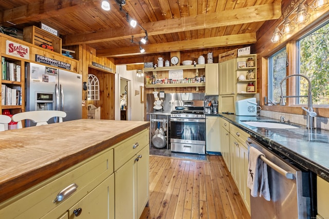 kitchen with stainless steel appliances, sink, beam ceiling, light hardwood / wood-style flooring, and wooden ceiling