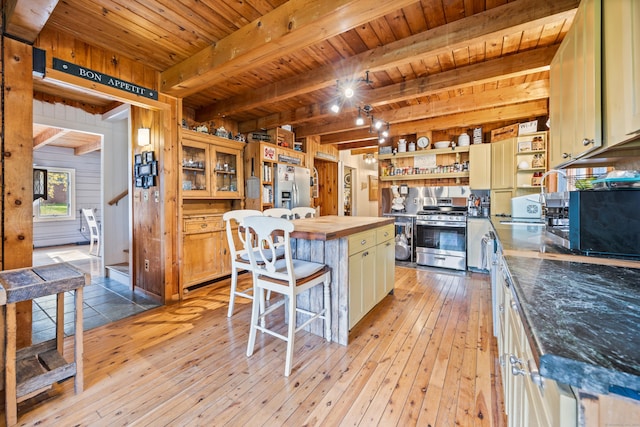 kitchen featuring a center island, stainless steel appliances, light hardwood / wood-style floors, and wood walls