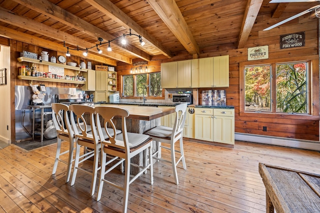 kitchen with beam ceiling, light hardwood / wood-style flooring, wooden walls, and wood ceiling