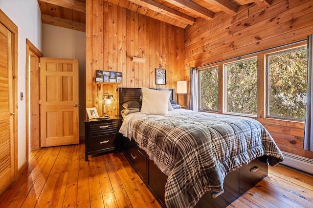 bedroom featuring wood walls, light hardwood / wood-style floors, beam ceiling, and wooden ceiling