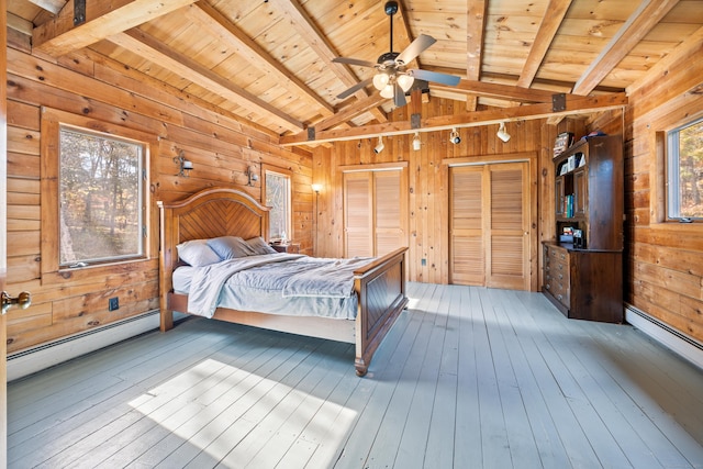 bedroom with wooden walls, baseboard heating, wood-type flooring, wood ceiling, and multiple closets