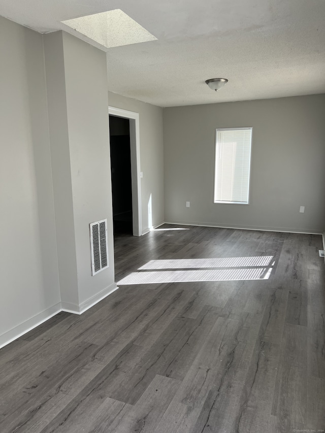 empty room with a textured ceiling and dark hardwood / wood-style floors