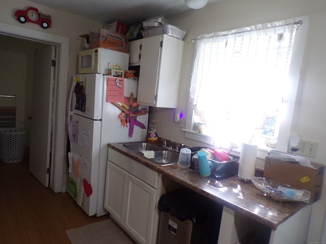 kitchen with white cabinetry, white appliances, sink, and hardwood / wood-style floors