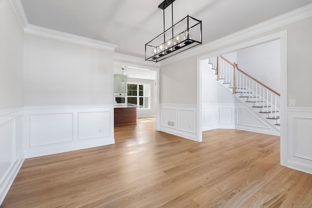 unfurnished dining area with crown molding, light hardwood / wood-style flooring, and a chandelier