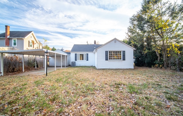 rear view of house featuring a lawn, central AC, and a carport