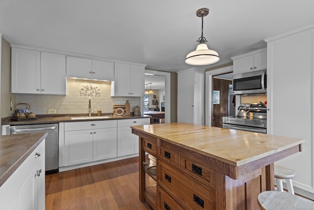 kitchen featuring white cabinets, sink, tasteful backsplash, decorative light fixtures, and stainless steel appliances