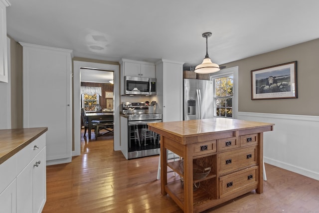 kitchen featuring wood counters, white cabinets, decorative light fixtures, wood-type flooring, and stainless steel appliances