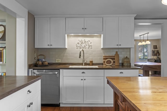 kitchen with butcher block countertops, stainless steel dishwasher, tasteful backsplash, and white cabinetry