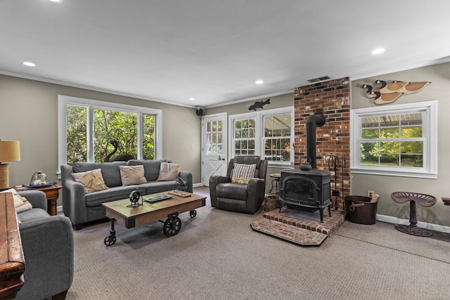 living room featuring a wood stove, crown molding, and carpet floors