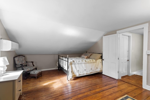 unfurnished bedroom featuring dark hardwood / wood-style flooring, vaulted ceiling, and a wall mounted AC