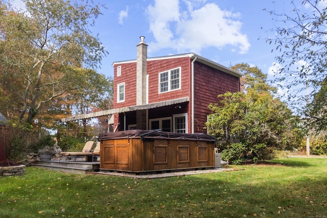 rear view of house featuring a yard and a hot tub