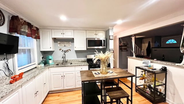 kitchen with appliances with stainless steel finishes, white cabinetry, sink, and light wood-type flooring