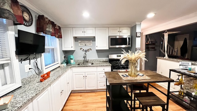 kitchen with sink, white cabinetry, stainless steel appliances, and light wood-type flooring