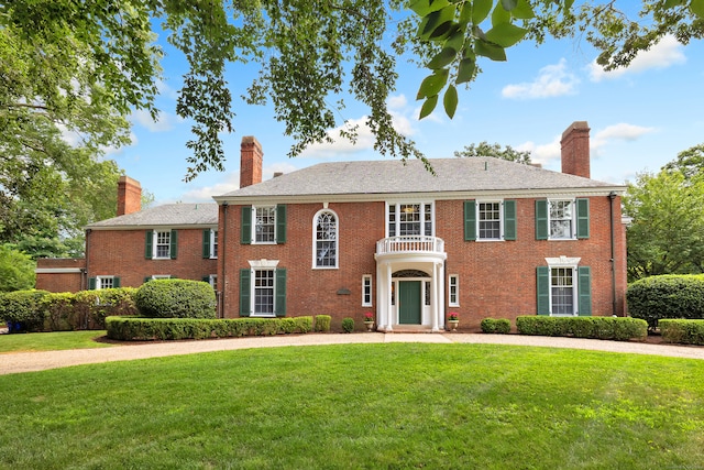 colonial inspired home with a balcony and a front lawn