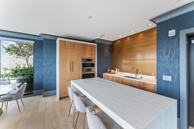 kitchen with a breakfast bar, light hardwood / wood-style floors, sink, and double oven