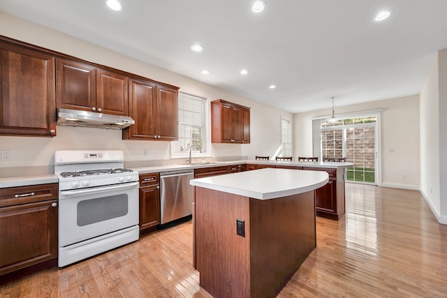 kitchen featuring a center island, light hardwood / wood-style floors, white range with gas cooktop, stainless steel dishwasher, and decorative light fixtures