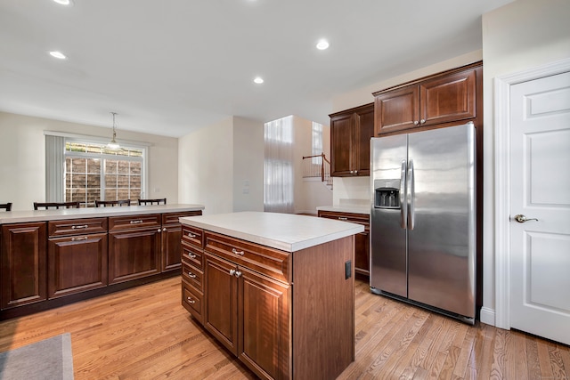 kitchen featuring light wood-type flooring, a center island, pendant lighting, and stainless steel fridge