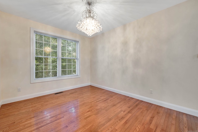 empty room featuring a chandelier and light wood-type flooring