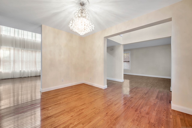 unfurnished room with a notable chandelier and wood-type flooring