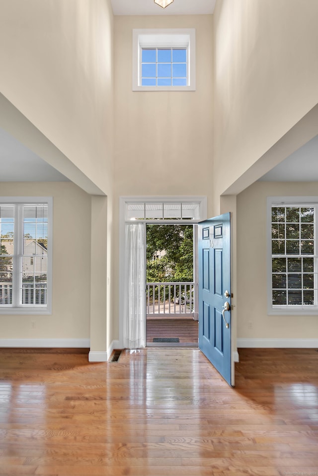 foyer entrance with light hardwood / wood-style floors and a towering ceiling