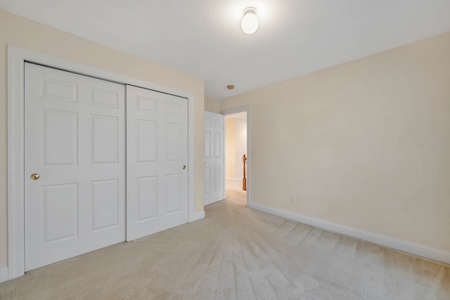 unfurnished bedroom featuring light colored carpet and a closet