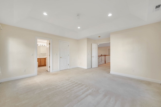 carpeted spare room featuring a tray ceiling