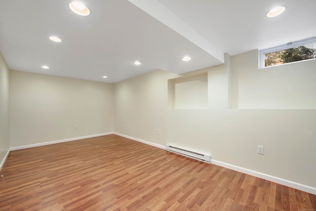 basement with a baseboard radiator and light hardwood / wood-style flooring