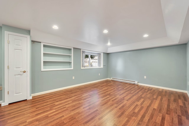 unfurnished room with built in features, hardwood / wood-style flooring, and a baseboard radiator