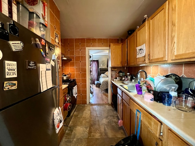 kitchen featuring tile walls, sink, refrigerator, and black range with gas cooktop