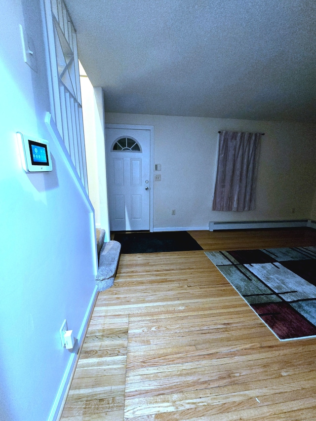 foyer entrance featuring light hardwood / wood-style flooring, a textured ceiling, and baseboard heating