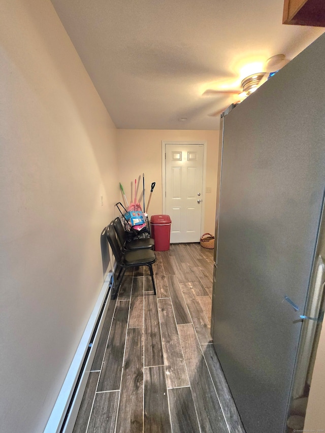 hallway with a baseboard heating unit and dark hardwood / wood-style flooring