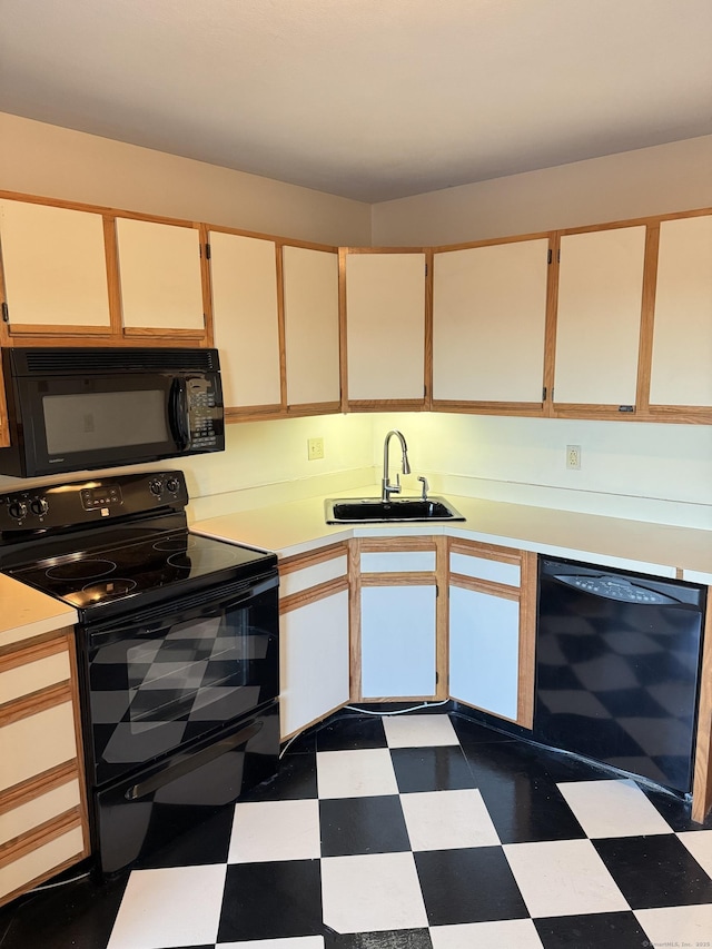 kitchen with black appliances, dark floors, a sink, and light countertops