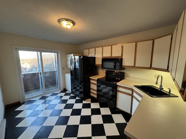 kitchen with washer / dryer, dark floors, light countertops, black appliances, and a sink