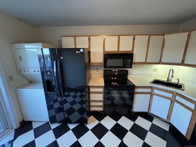 kitchen featuring dark floors, stacked washer and dryer, light countertops, a sink, and black appliances