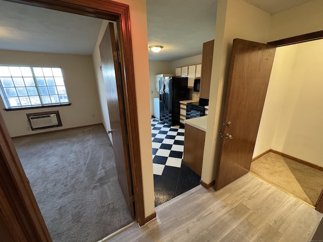 hall with light floors, a wall mounted AC, and baseboards