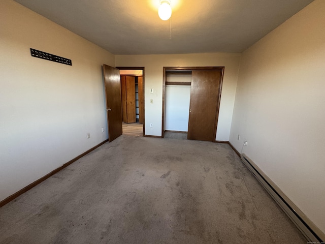 unfurnished bedroom with a baseboard radiator, a closet, baseboards, and carpet flooring