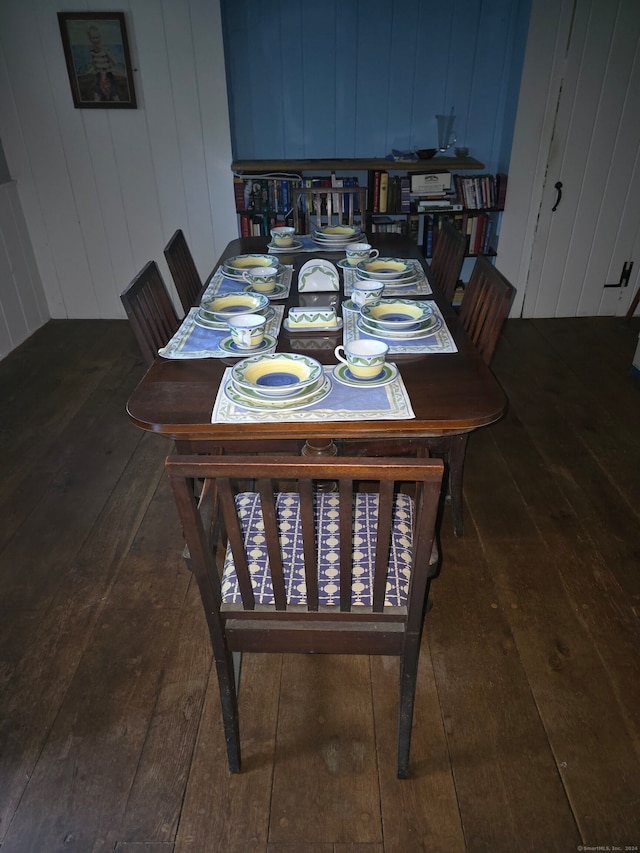 dining area with wooden walls and dark hardwood / wood-style floors