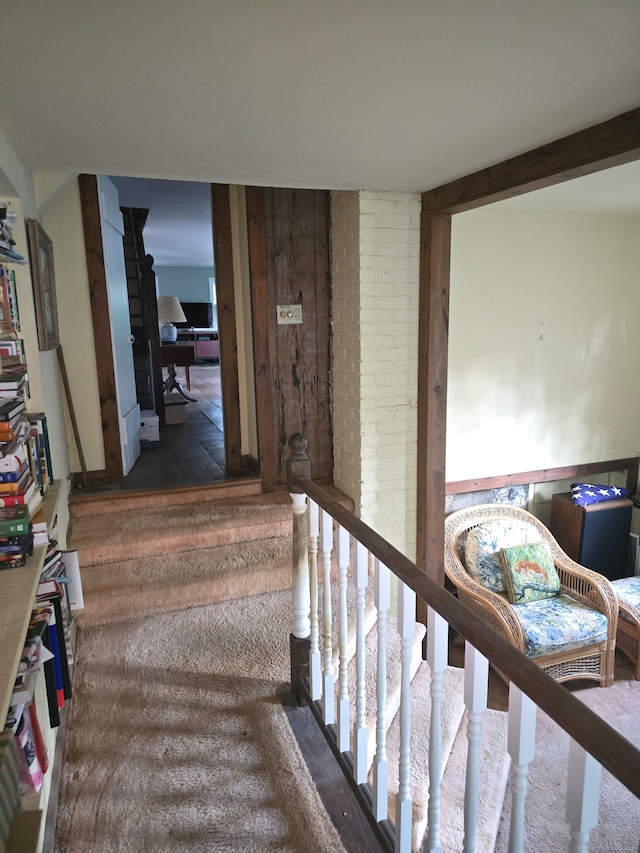 staircase with carpet floors and brick wall