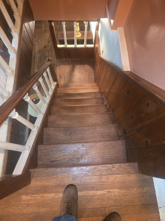 stairway with wood walls and hardwood / wood-style flooring