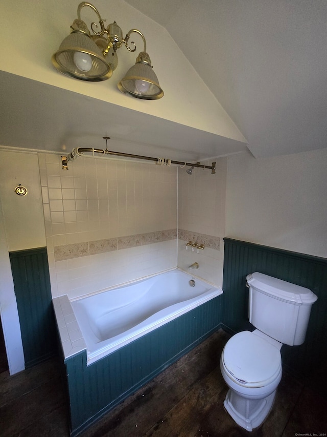 bathroom with toilet, a relaxing tiled tub, lofted ceiling, and hardwood / wood-style floors