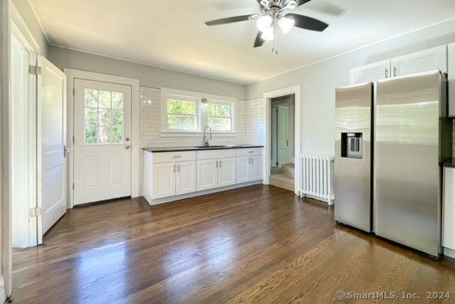 kitchen with sink, radiator heating unit, white cabinetry, dark wood-type flooring, and stainless steel refrigerator with ice dispenser