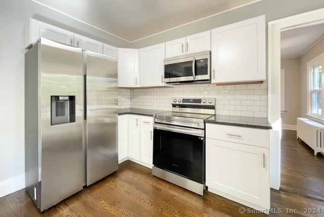 kitchen with white cabinets, radiator, stainless steel appliances, and dark wood-type flooring